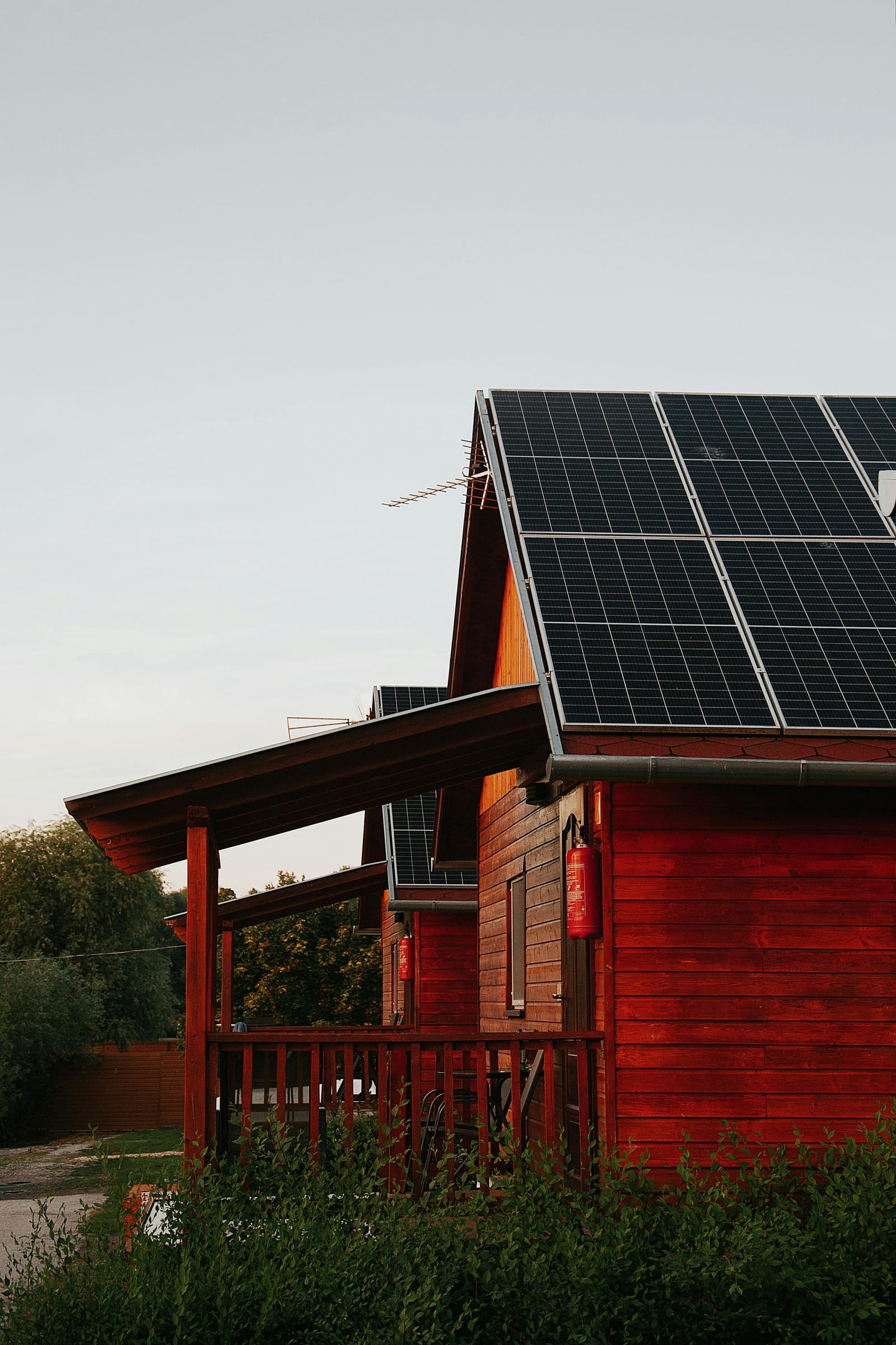 Solar panels on the steep roof of a red barn-style farmhouse