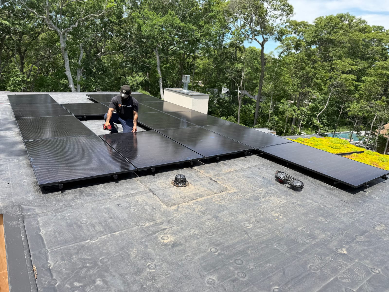 Installer working on a newly finished rooftop solar array with woodland behind