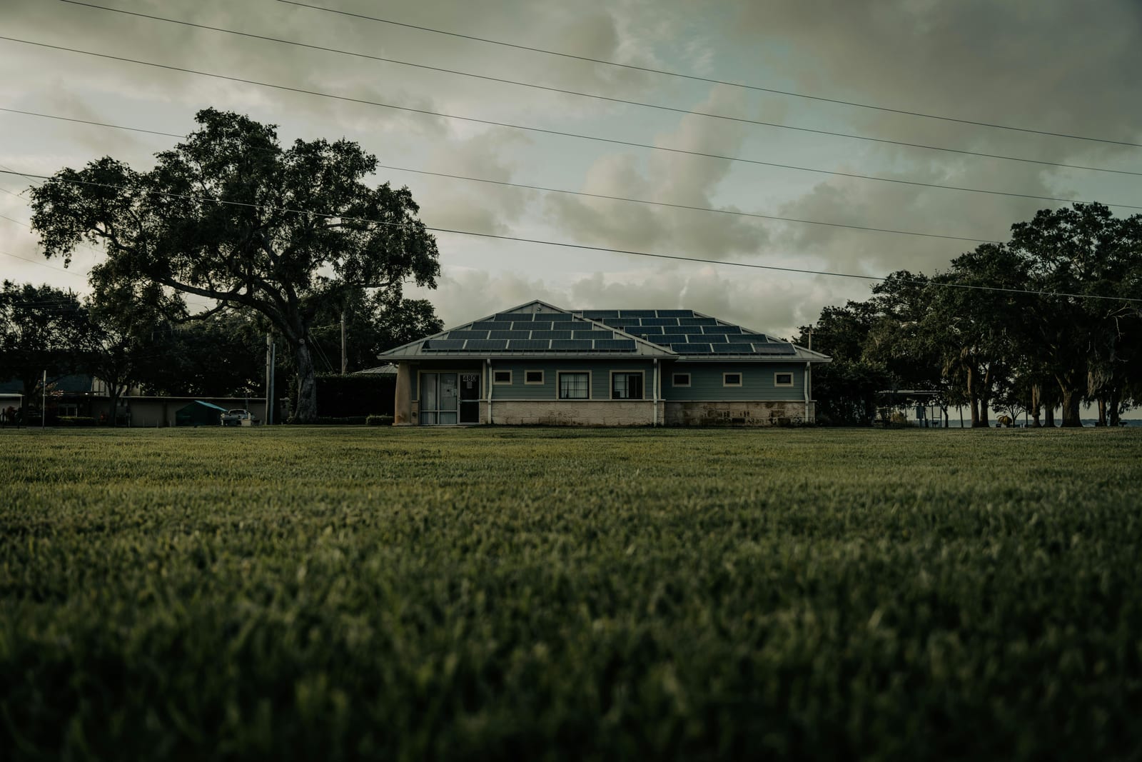 Farmhouse beyond open fields under a cloudy sky