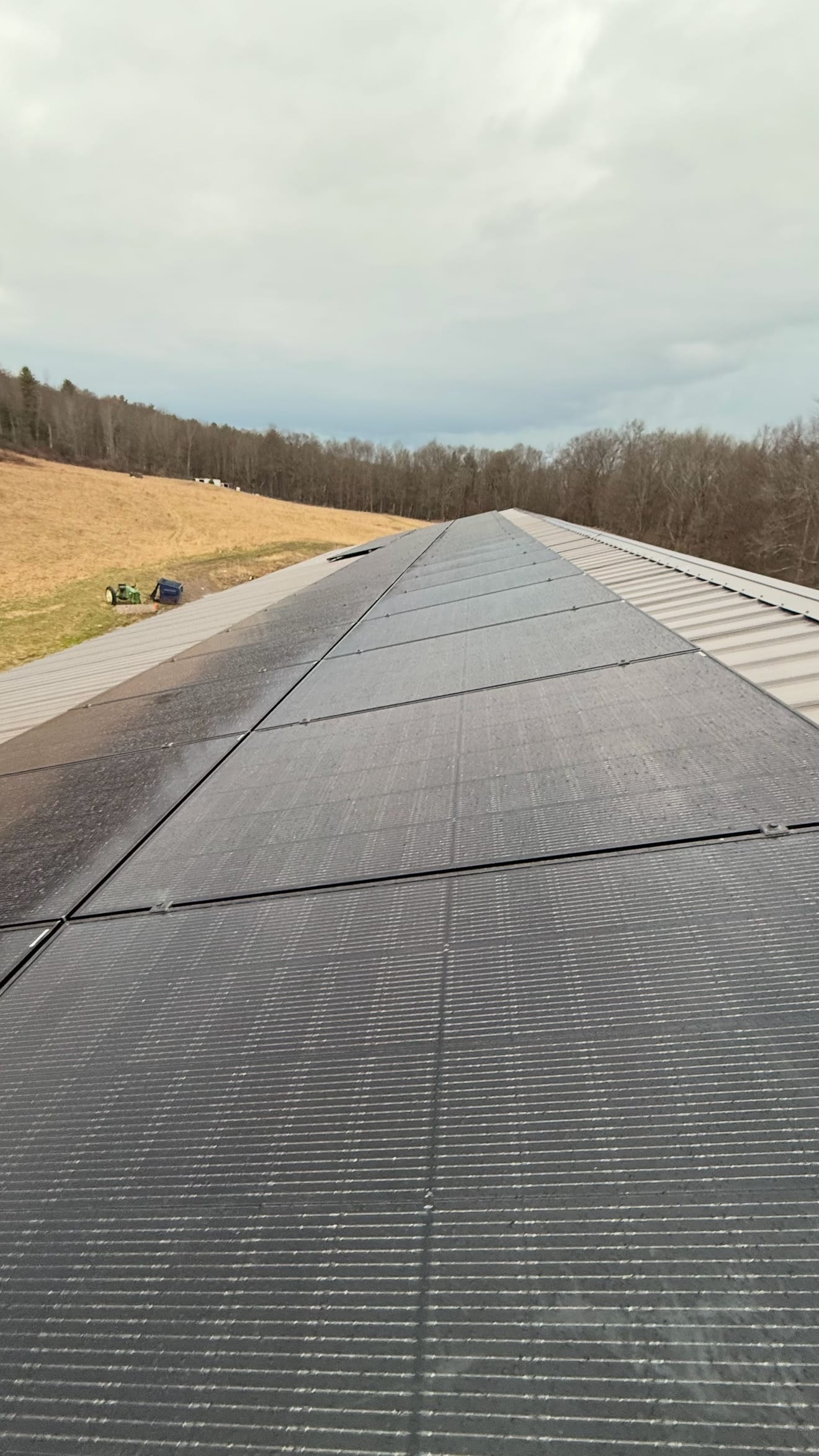 Long run of solar panels along a roof beside open farmland