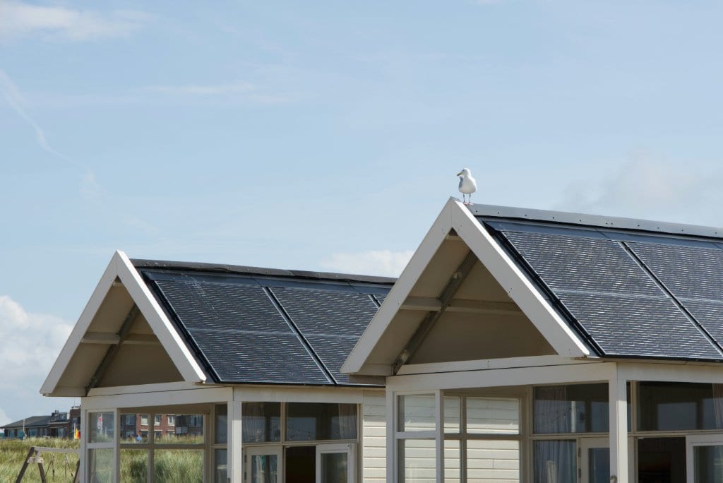 Technician carefully inspecting solar panels on a refined Hamptons residence